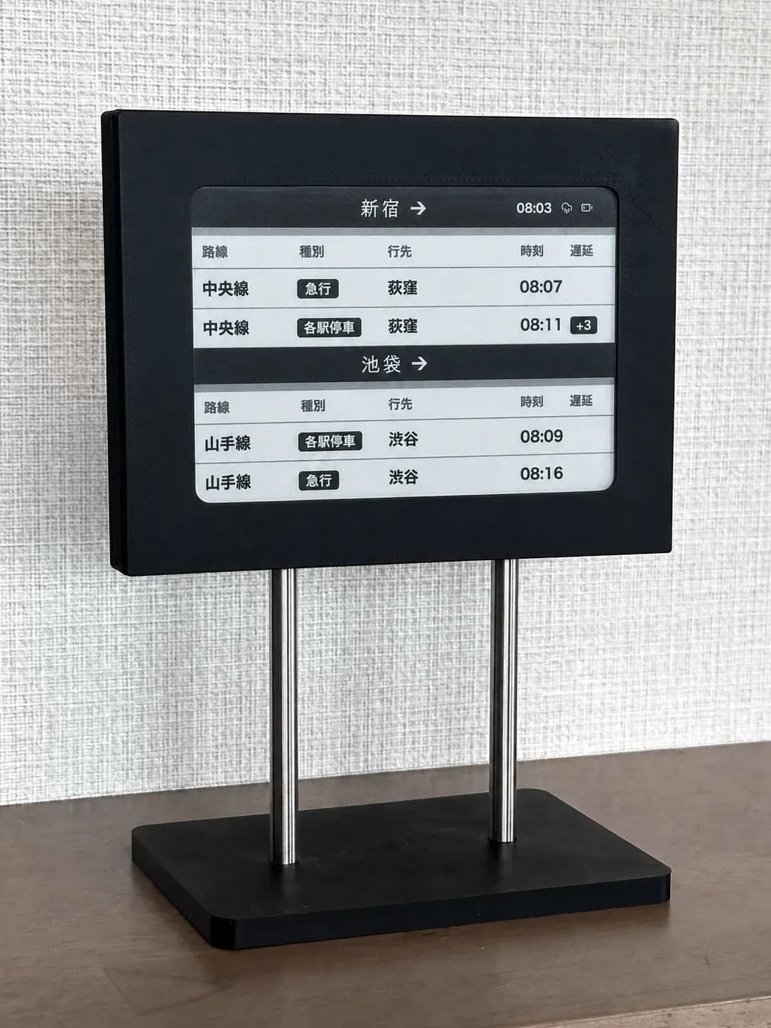 EkiBoard e-ink display on its desk stand, showing upcoming train departures